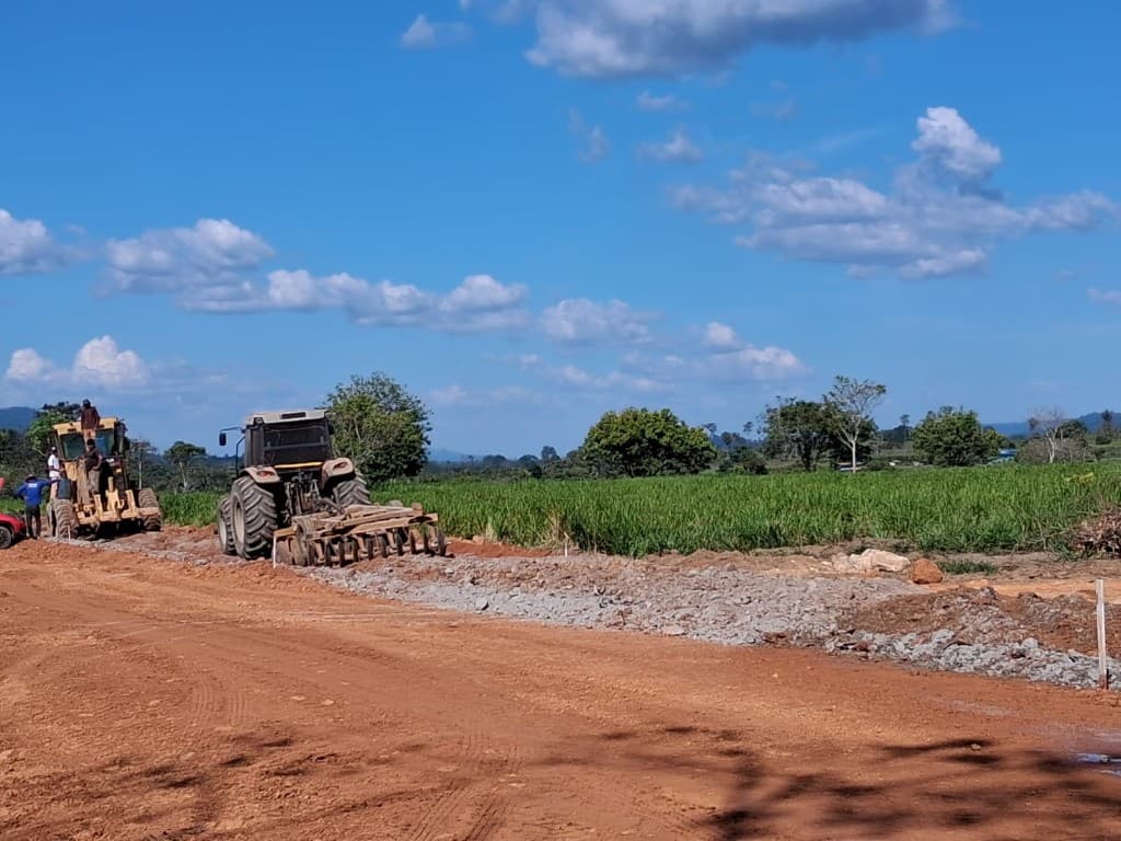 Trator com grade de discos e motoniveladora em obra de preparação de base viária