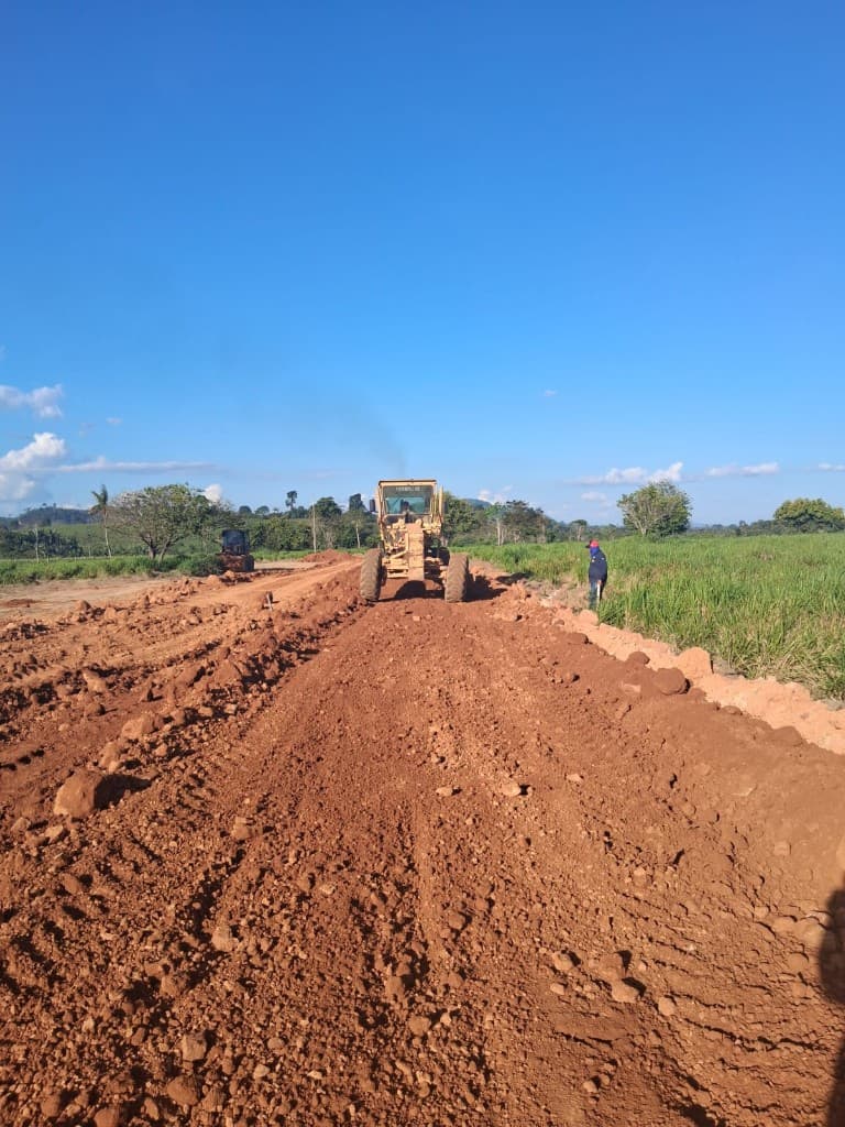 Motoniveladora Caterpillar operando em terraplanagem de estrada de terra avermelhada