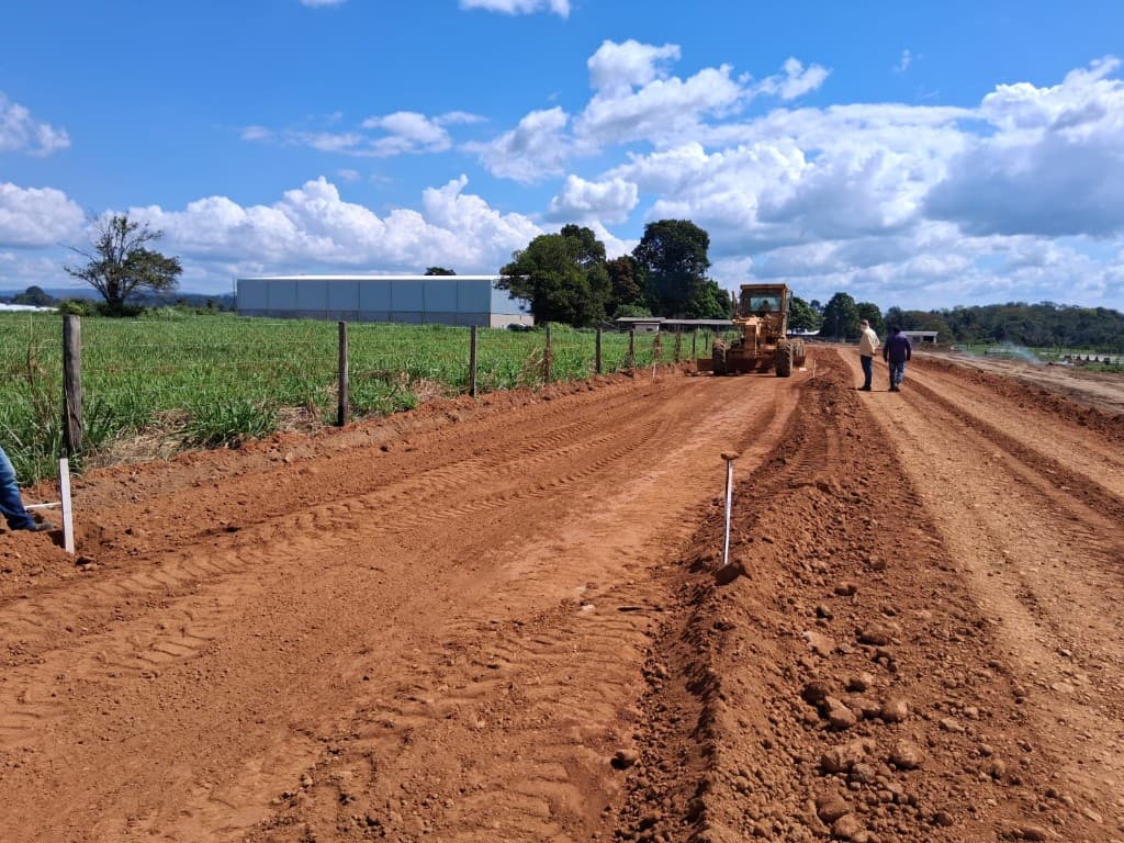 Equipe técnica supervisionando motoniveladora em obra de abertura de estrada
